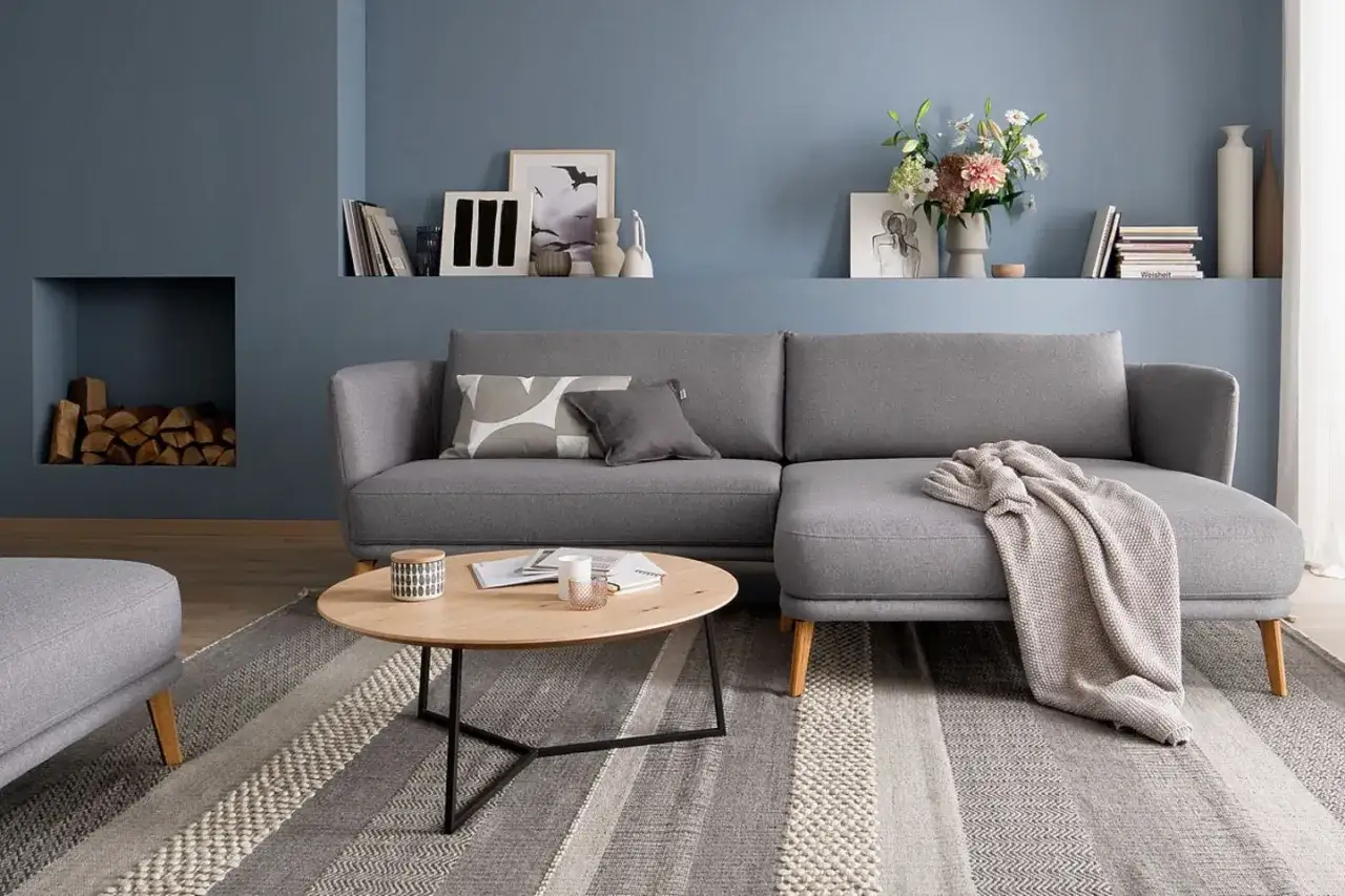 Gemütliches kleines Wohnzimmer skandinavisch einrichten mit grauem Sofa, Holztisch und Kamin.