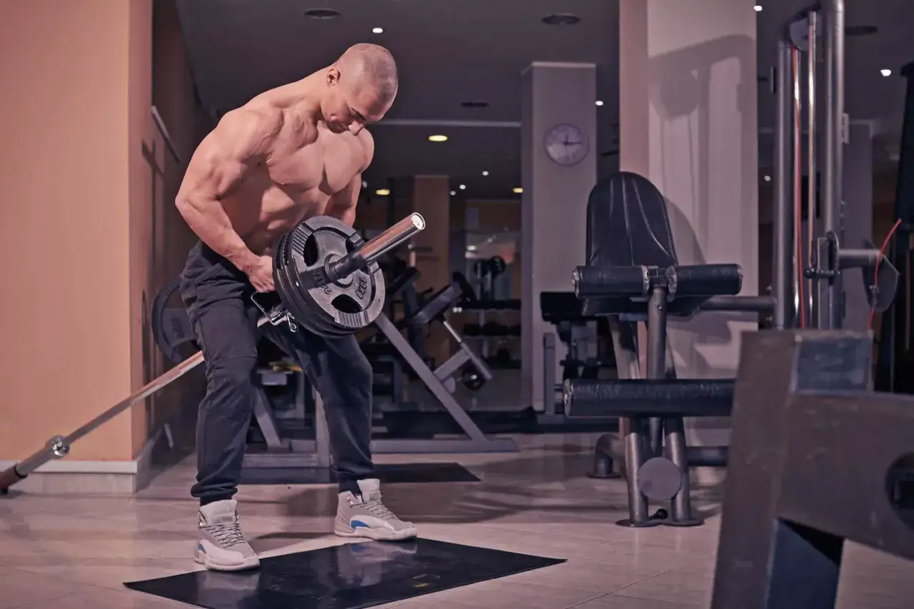 Muskulös man utför en t bar row i ett gym.