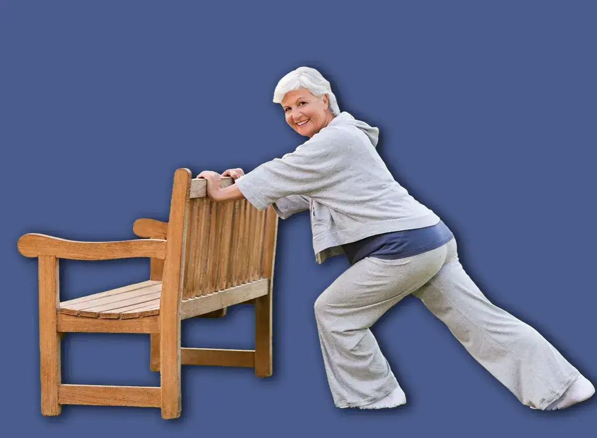 Une femme souriante s'étire en s'appuyant sur un banc en bois, un exercice simple pour comment retrouver de la force dans les jambes.