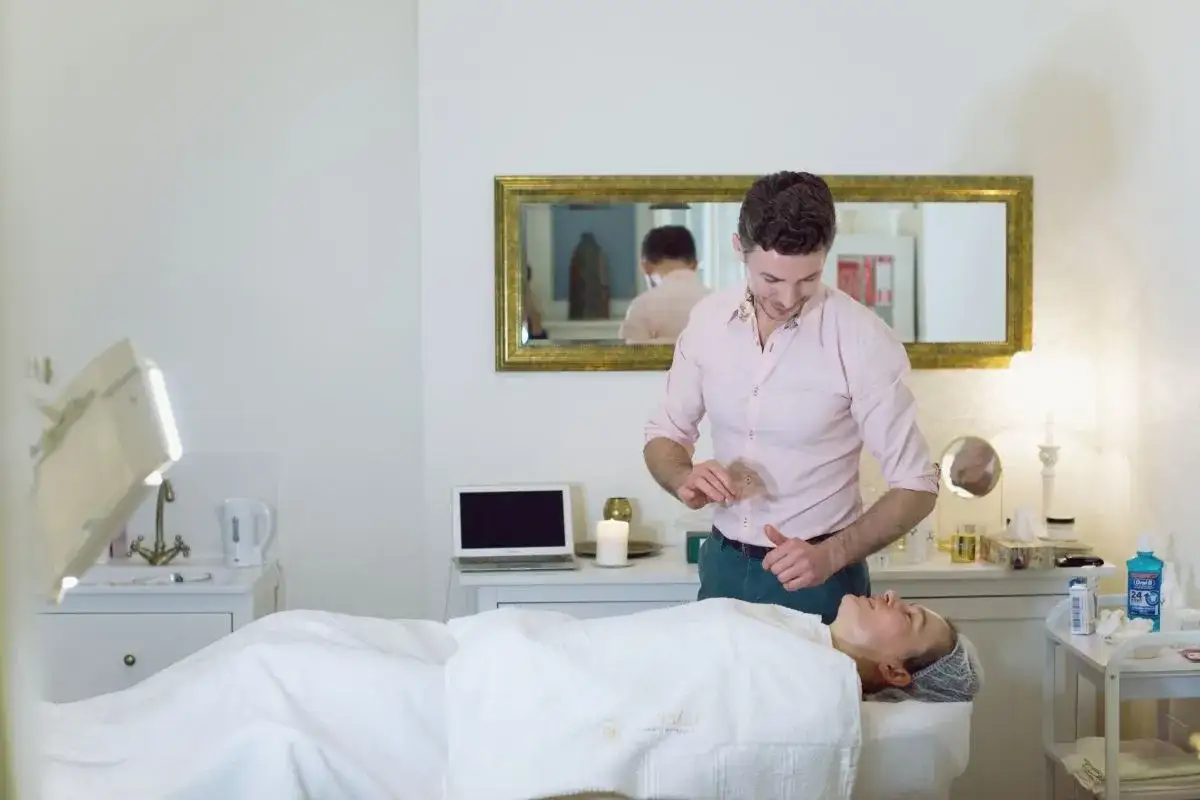 Terapeuta wykonuje drenaż limfatyczny twarzy. Delikatne ruchy poprawiają krążenie i redukują obrzęki.