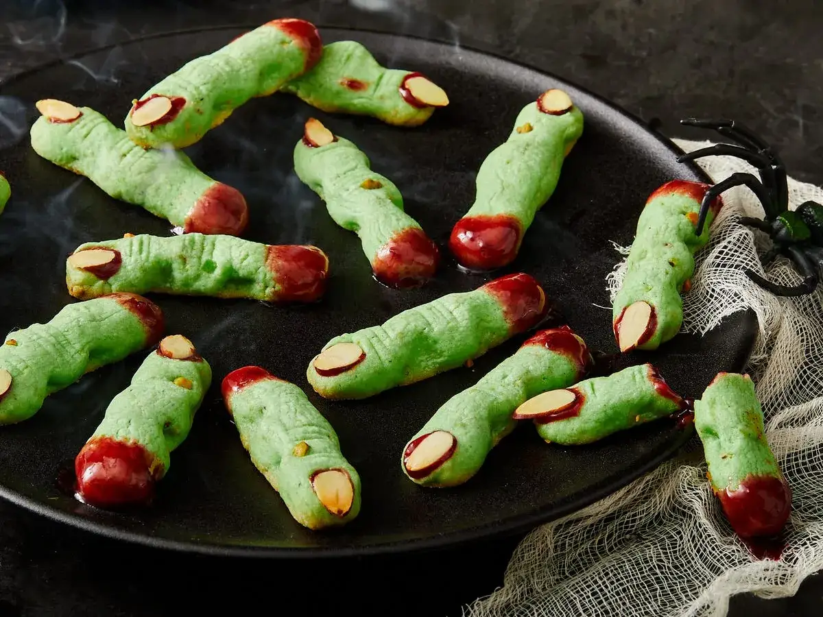 Gruselige Snacks: grüne Kekse in Fingerform mit Mandel-Fingernägeln und rotem Zuckerguss als Blut.