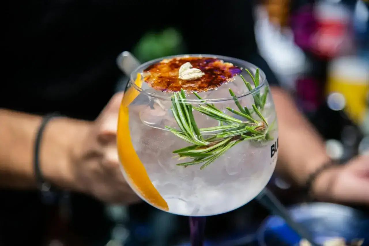 Gin z tonikiem z pomarańczą i gałązką rozmarynu. Efekt dodania świeżego rozmarynu jest widoczny w aromacie i dekoracji.