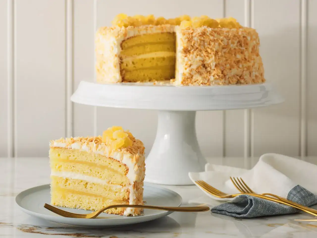 Saftige Pina Colada Torte mit Kokosraspeln und Ananasst&uuml;cken, ein St&uuml;ck auf einem Teller, bereit zum Genie&szlig;en.
