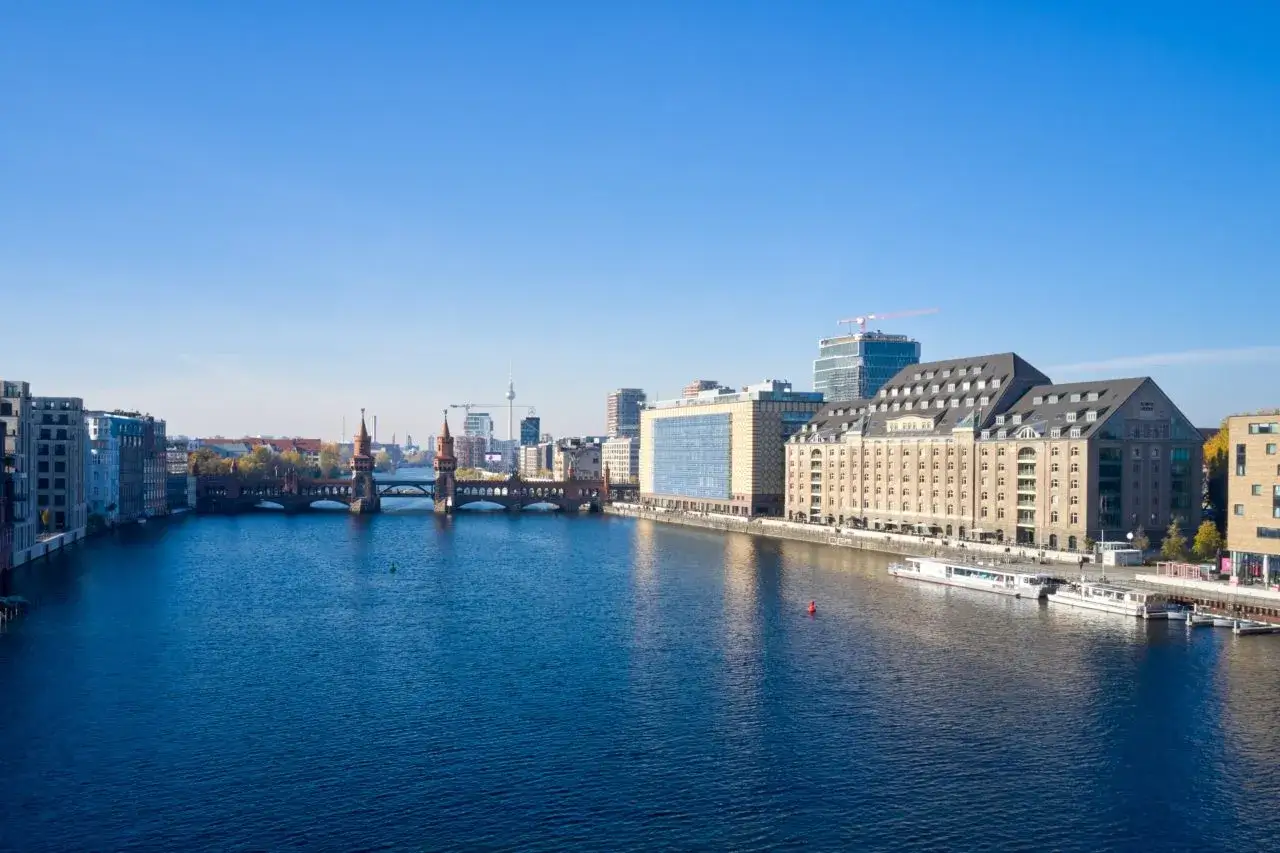 Blick auf die Spree mit der Oberbaumbrücke und modernen Gebäuden, darunter die Rivo Spreeterrassen.