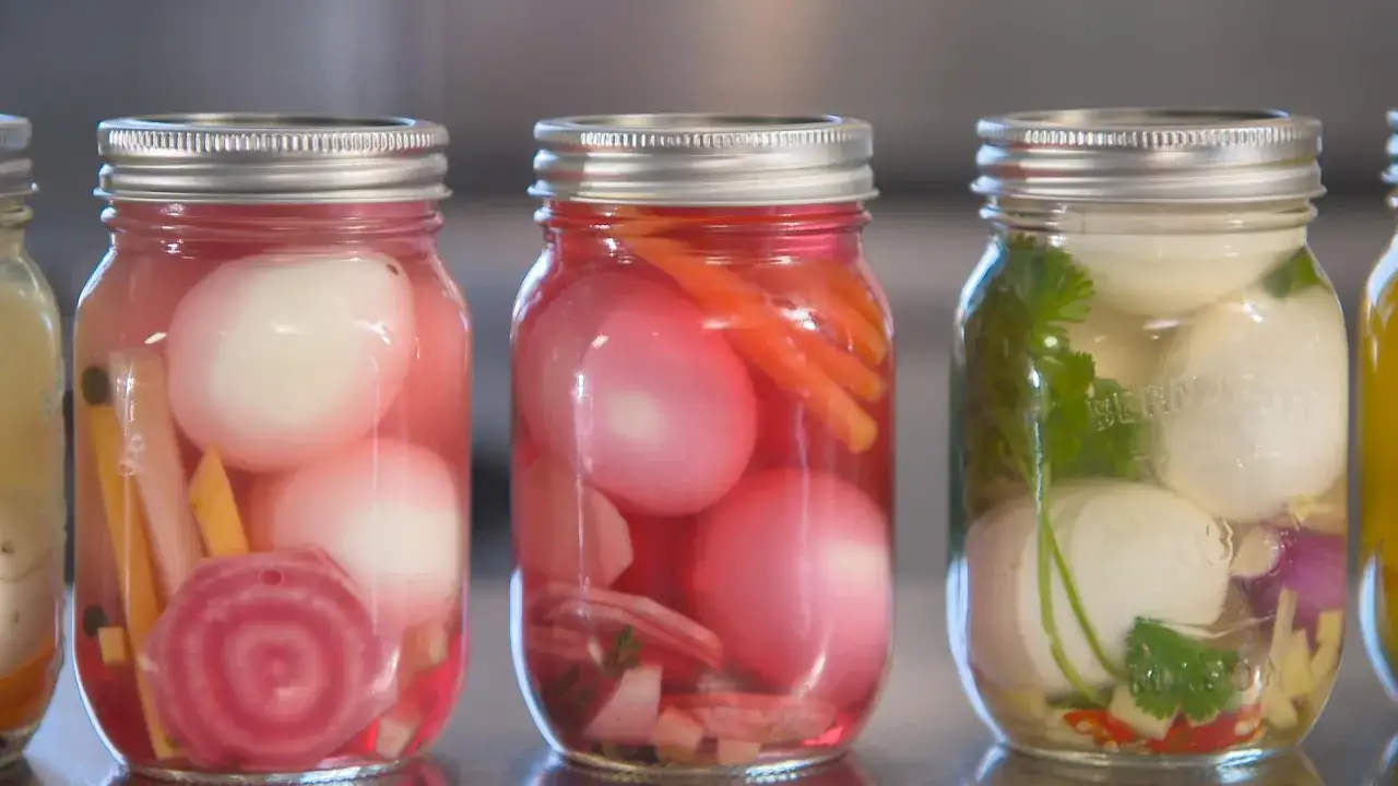Trois bocaux de conserves : un avec des &oelig;ufs et des betteraves, un autre avec des &oelig;ufs et des carottes, et un troisi&egrave;me avec des &oelig;ufs, des herbes et des piments. L'oeuf rouge est dans le premier bocal.