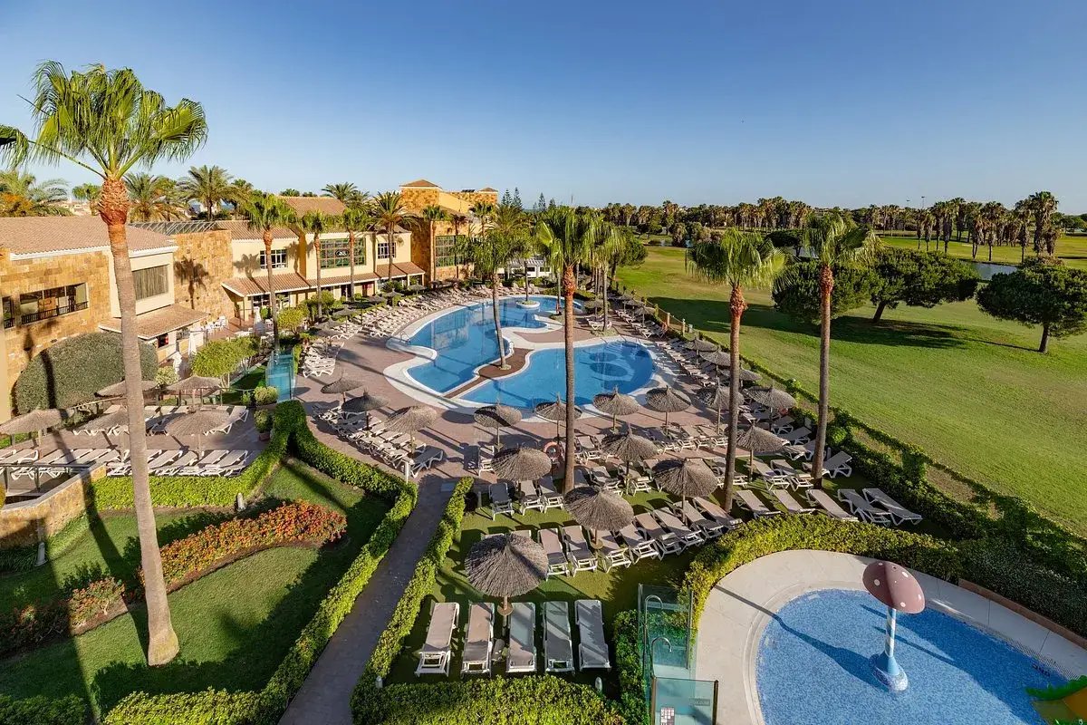 Resort con piscina y palmeras, ideal para encontrar last minute hotel deals y disfrutar del sol.