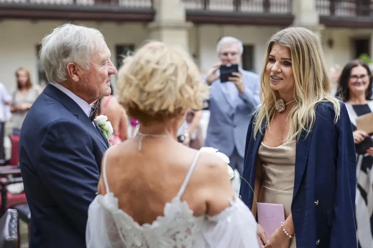 Elegancki pan w garniturze, młoda kobieta z naszyjnikiem i starsza pani rozmawiają. Czy Gerard z Sanatorium Miłości ma tyle lat?