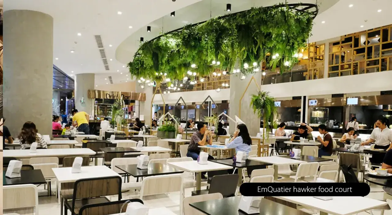 Un food court moderno con mesas y gente comiendo. El significado de food court es un área de comidas en un centro comercial o similar.