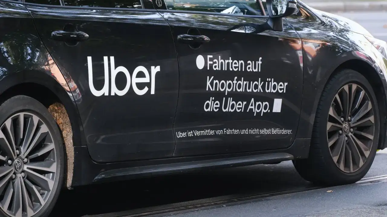 Schwarzer Uber-Wagen mit weißem Logo. Hier erfährst du, wie kann man über Fahrer werden und Fahrten über die App buchen.