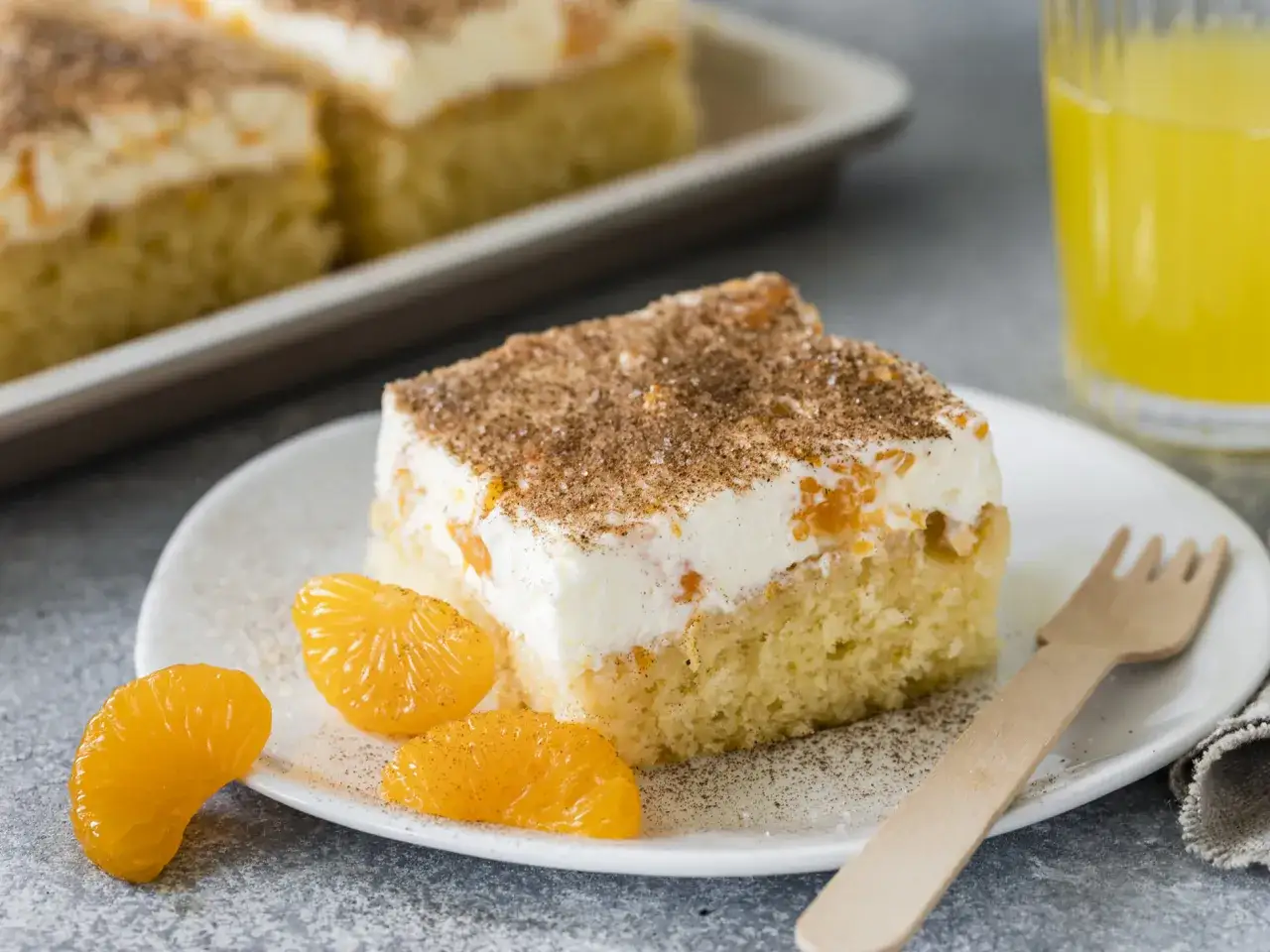 Ein St&uuml;ck saftiger Fantakuchen mit cremiger F&uuml;llung und Mandarinenst&uuml;cken, bestreut mit Zimt. Perfekt f&uuml;r das Fantakuchen Rezept!