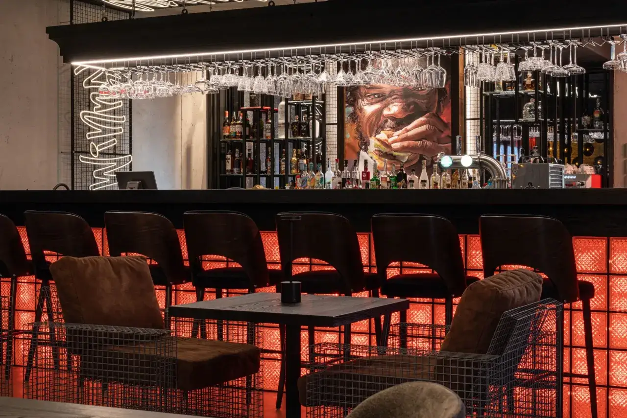 Nowoczesny bar z neonowym napisem i obrazem mężczyzny jedzącego burgera. Idealne miejsce, gdzie zjeść w Nowym Targu.