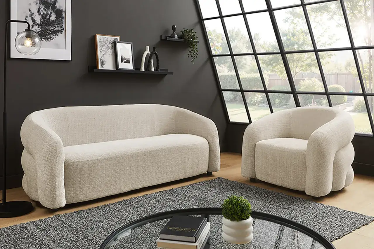 Ein beiges Sofa und ein Sessel, was ist eine couch? Gem&uuml;tliche Sitzm&ouml;bel in einem modernen Wohnzimmer mit gro&szlig;em Fenster.