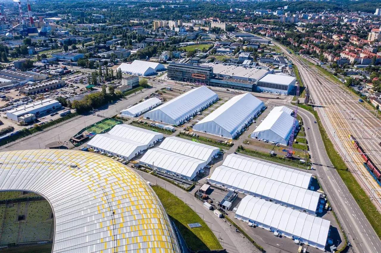 Duże białe hale namiotowe w pobliżu stadionu, tworzące tymczasowe centrum logistyczne. Letnica Gdańsk w pełnej krasie.