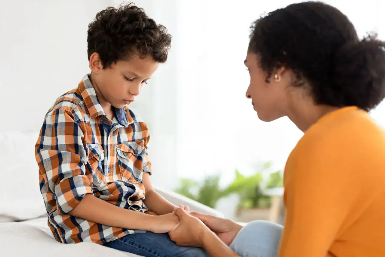 Madre consuela a su hijo, habl&aacute;ndole con empat&iacute;a. Aprende c&oacute;mo evitar que le hagan bullying a mi hijo.