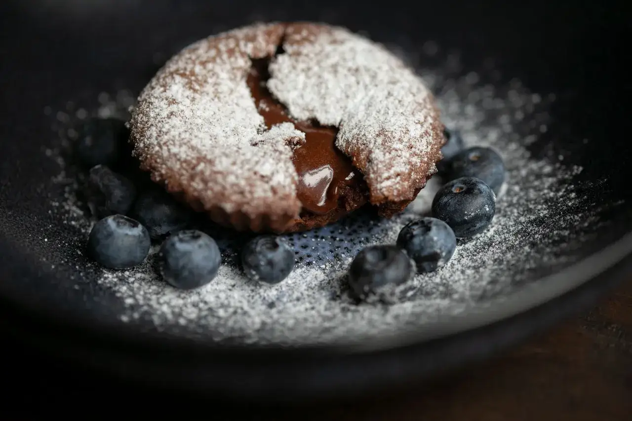 Ein warmer Moelleux au chocolat mit fl&uuml;ssigem Kern, best&auml;ubt mit Puderzucker und garniert mit Blaubeeren.