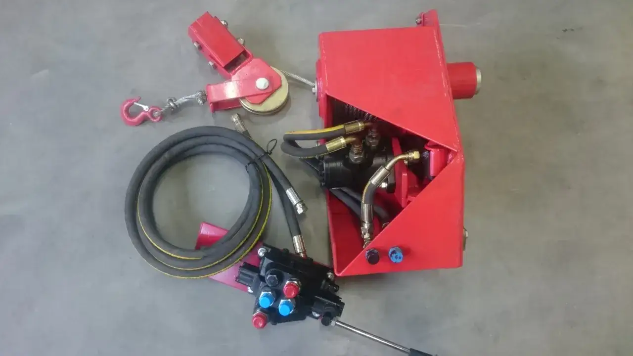 Rotes Schwenkwerk mit Hydraulikaggregat, Seilwinde, Schlauch und Bedienhebel.