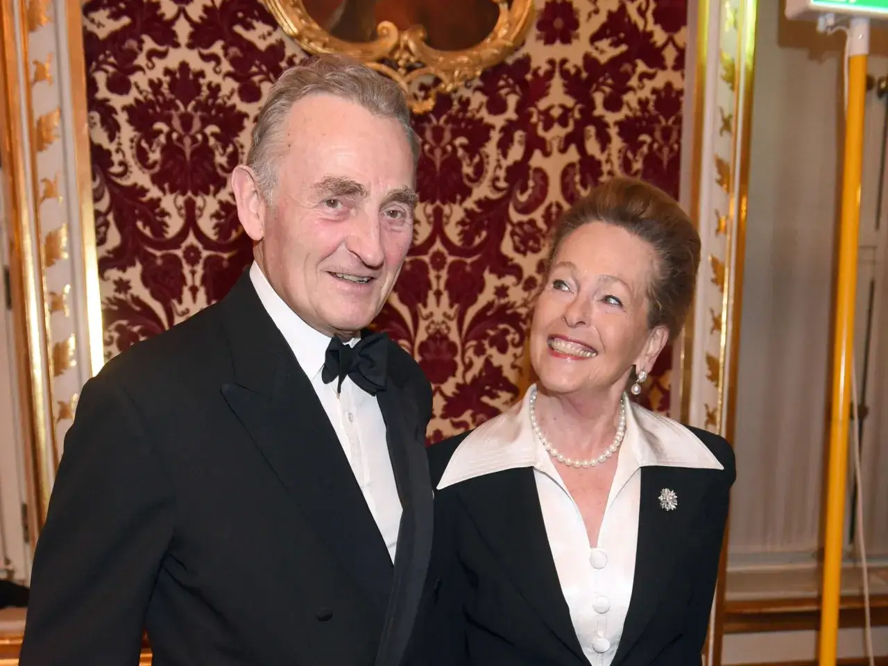 Max Emanuel Herzog in Bayern, elegant gekleidet, l&auml;chelt neben einer Dame mit Perlenkette.