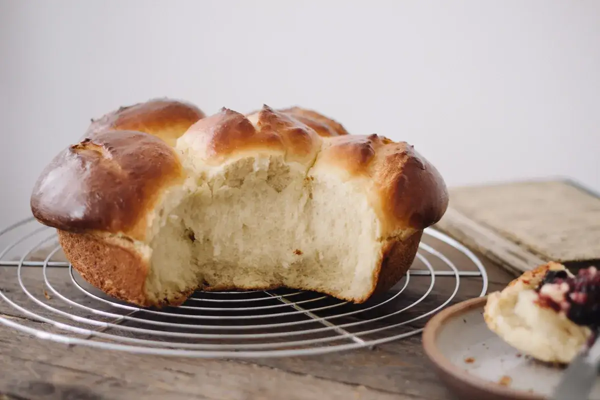 Brioche dorée et moelleuse, parfaite pour une recette brioche facile. Une part est déjà dégustée, révélant sa mie aérée.