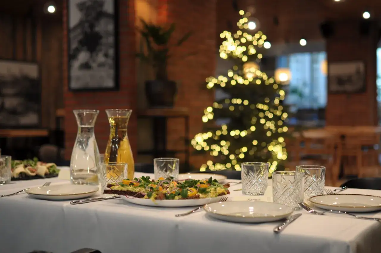 Elegancki catering na Boże Narodzenie: nakryty stół, przystawki i choinka w tle.