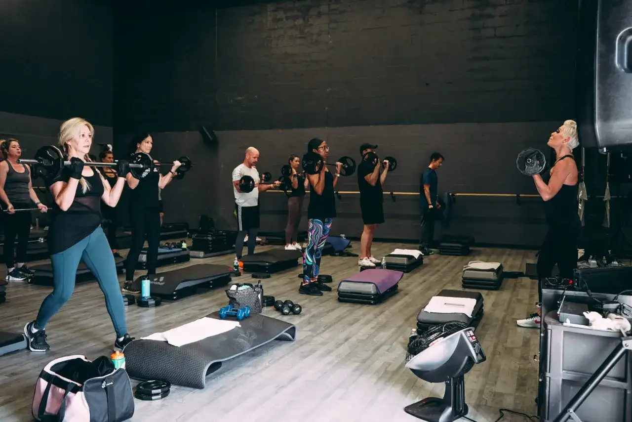 Grupa ćwiczy z ciężarami, tbc co to znaczy? Trening siłowy w sali gimnastycznej.