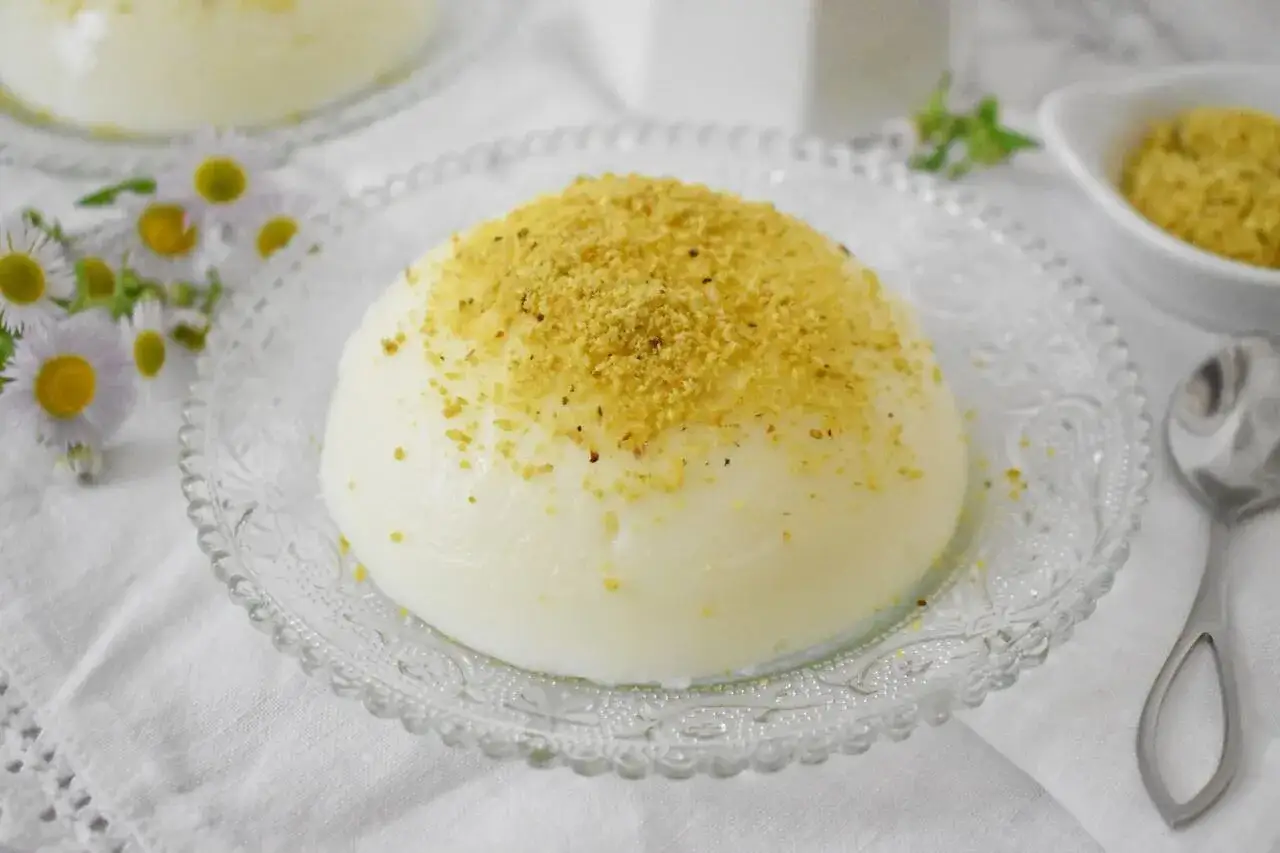 Panna cotta posypana pistacjami, jeden z wielu pysznych włoskich słodyczy, podana na ozdobnym talerzyku.