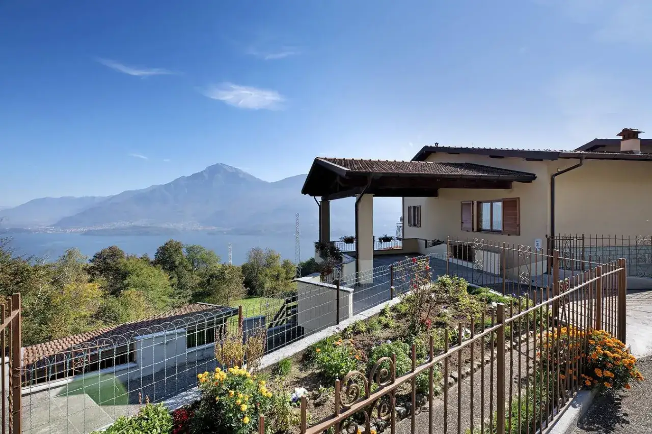Casa con vista lago, perfetta per idee weekend nord Italia. Giardino fiorito e montagne sullo sfondo.