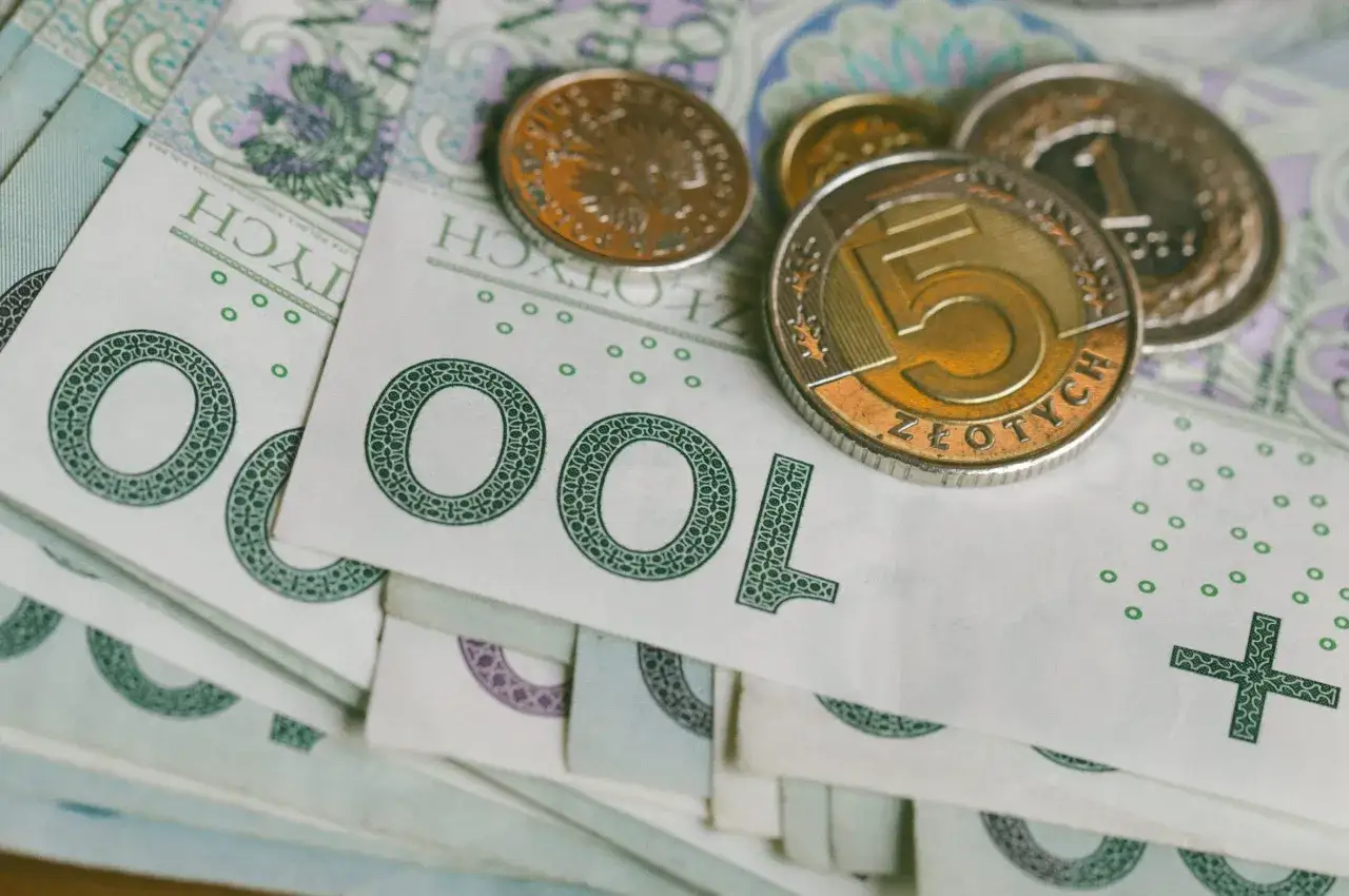 Stos monet i banknotów 100 zł. Może to być wynagrodzenie postojowe, które czeka na wypłatę.