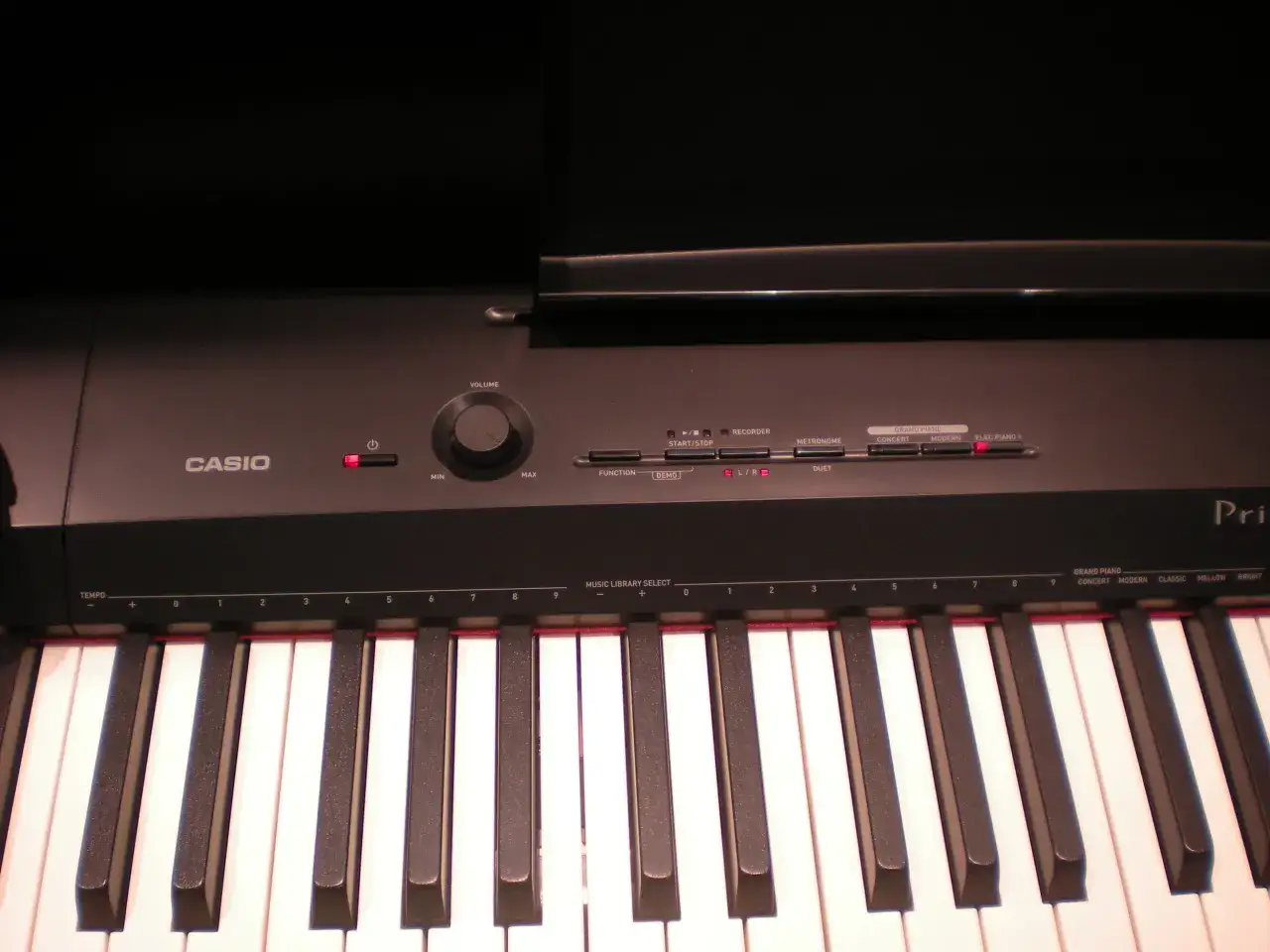 Klawiatura pianina cyfrowego firmy Casio z widocznymi przyciskami funkcji, pokrętłem głośności i białymi klawiszami.