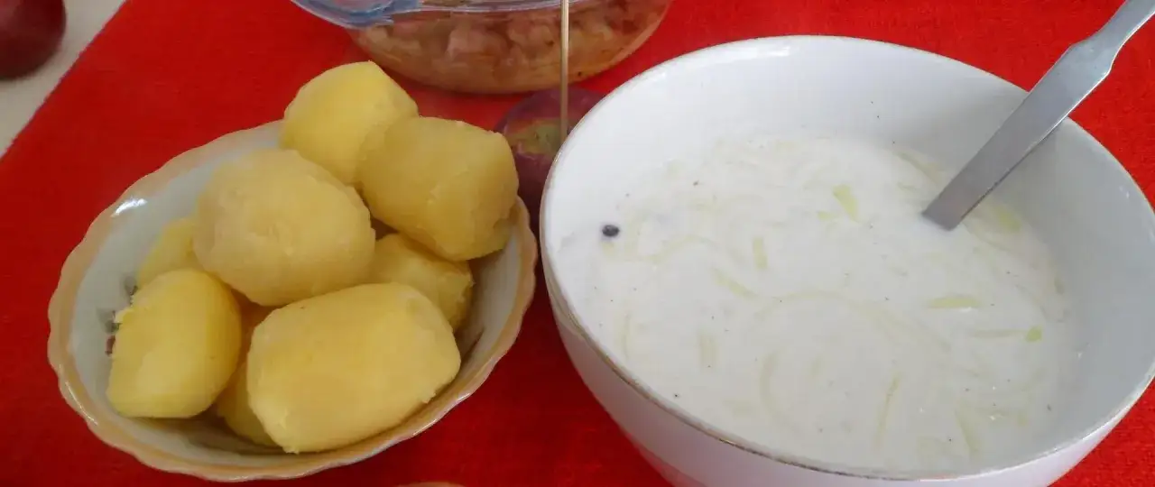 Ania gotuje zupę śledziową. Na stole są ziemniaki i miska z zupą.