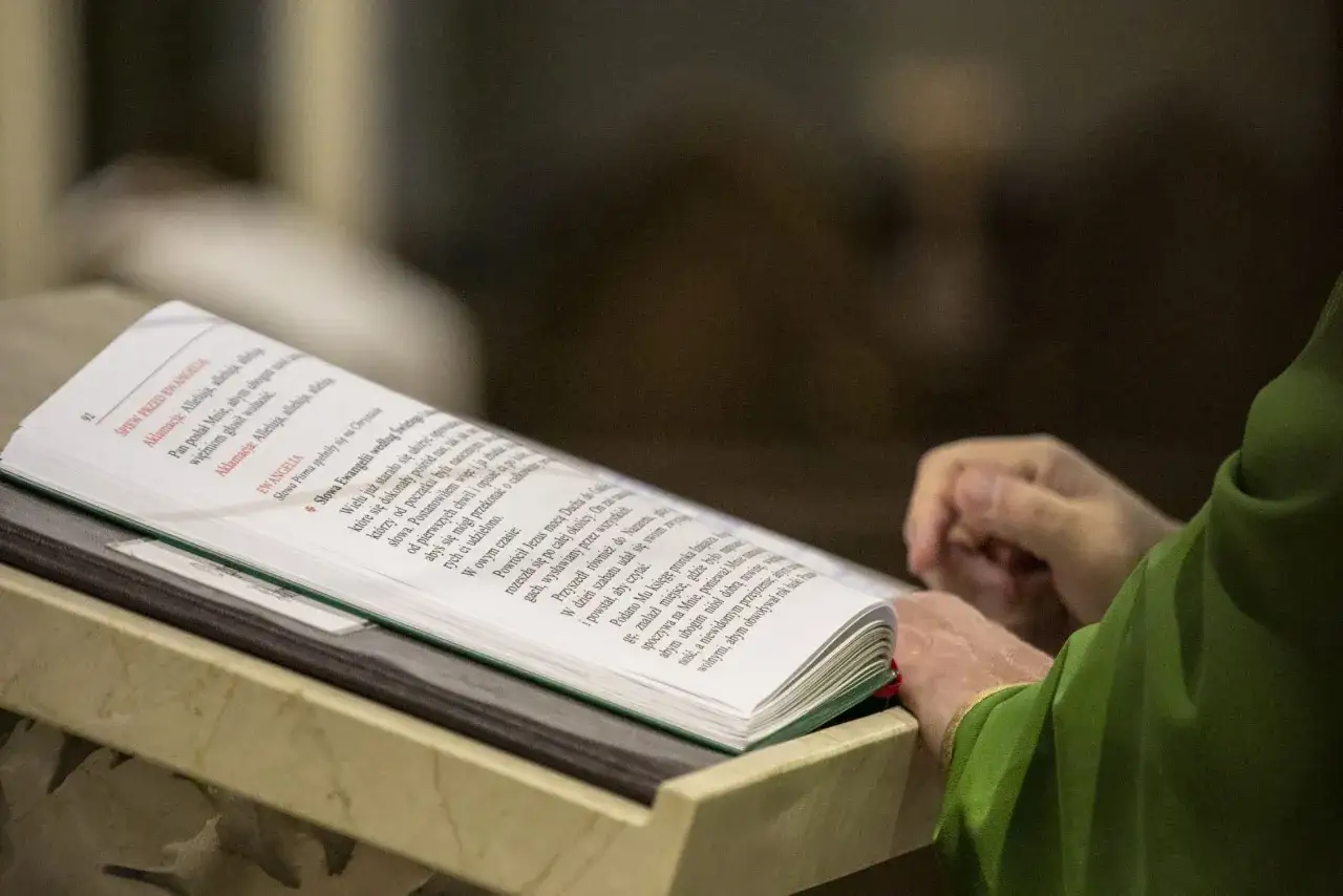 Osoba w zielonej szacie czyta księgę z tekstami liturgicznymi. Warto szukać mądrości syracha cytaty w świętych księgach.