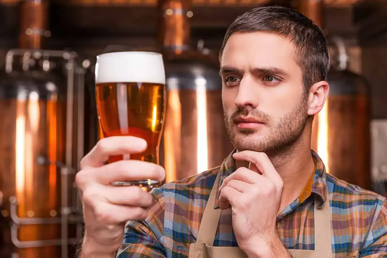 Uomo con birra in mano, in un birrificio. Pensa a una birra piccola calorie.