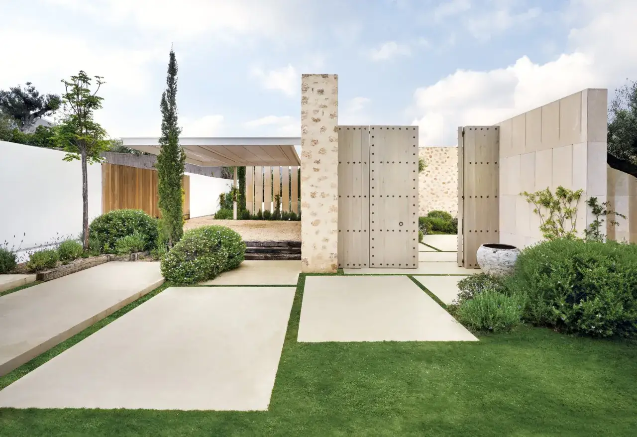 Modernas casas con patio interior central, con puertas de madera rústica y piedra, rodeadas de césped y vegetación exuberante.