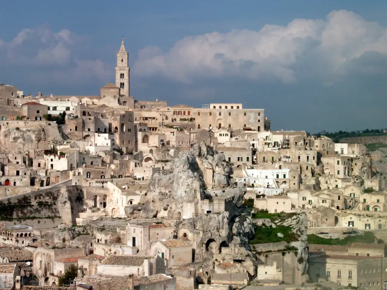Ancient cave dwellings and stone buildings cascade down a hillside in Matera, Italy. Explore this historic city to discover unique architecture and breathtaking views.