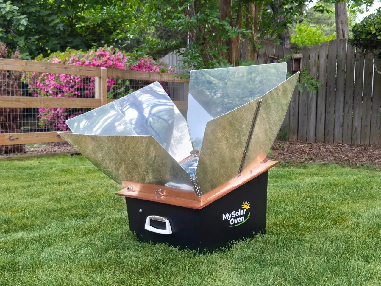 Un four solaire ouvert sur l'herbe, ses réflecteurs brillants captent la lumière du soleil pour illustrer le four solaire fonctionnement.
