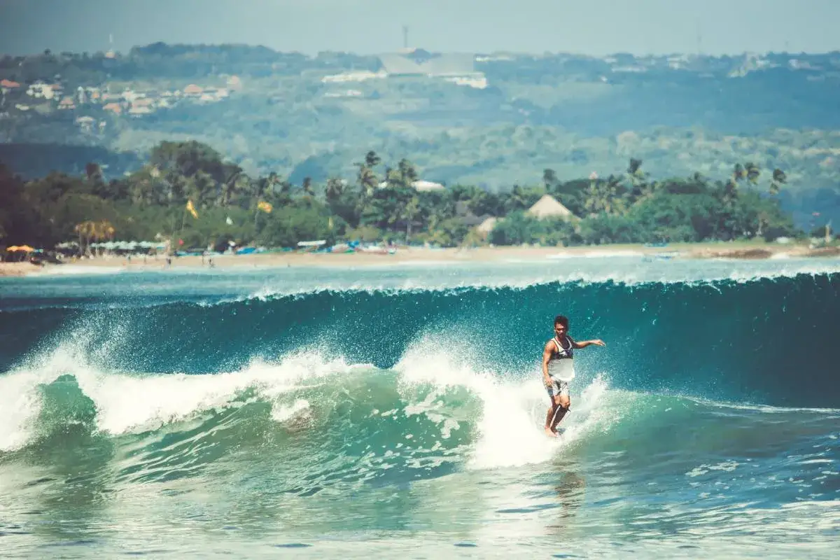 Surfer na fali. Idealny dzień, by wiedzieć, kiedy jechać na Bali i poczuć ten klimat.