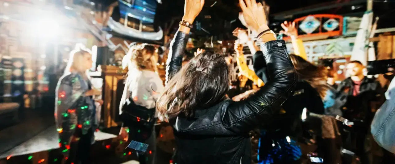 Menschen tanzen ausgelassen in einem Club, die Lichter blinken. Ein Gef&uuml;hl von Freiheit und Spa&szlig;, wie auf der Reeperbahn in Berlin.