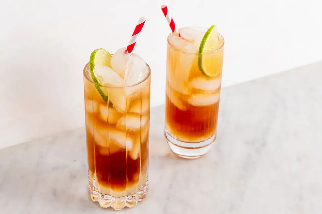 Två glas med Long Island Iced Tea, fyllda med is, lime och röda/vita sugrör.