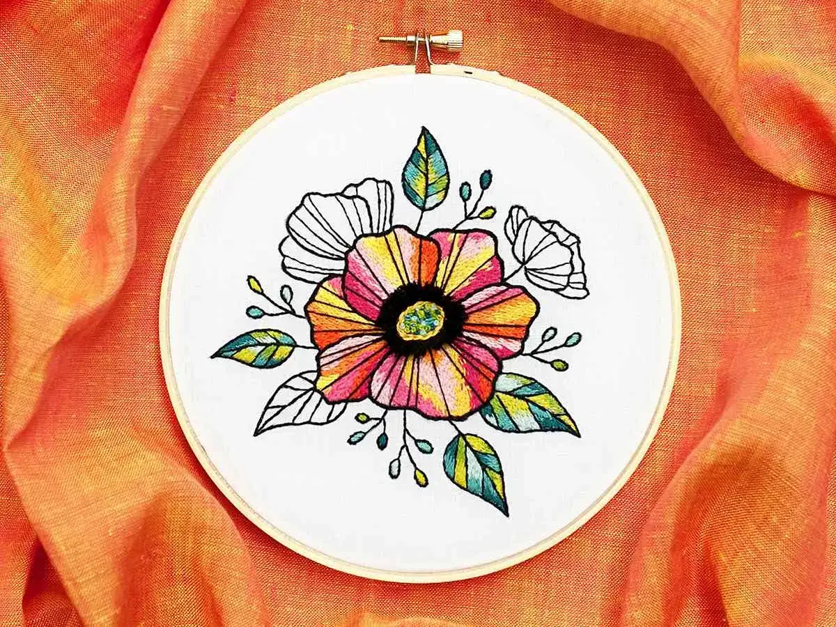 Hermoso bordado de flores y hojas sobre tela blanca, con vibrantes colores y contornos negros. Inspiraci&oacute;n para dibujos bordar sobre lana.