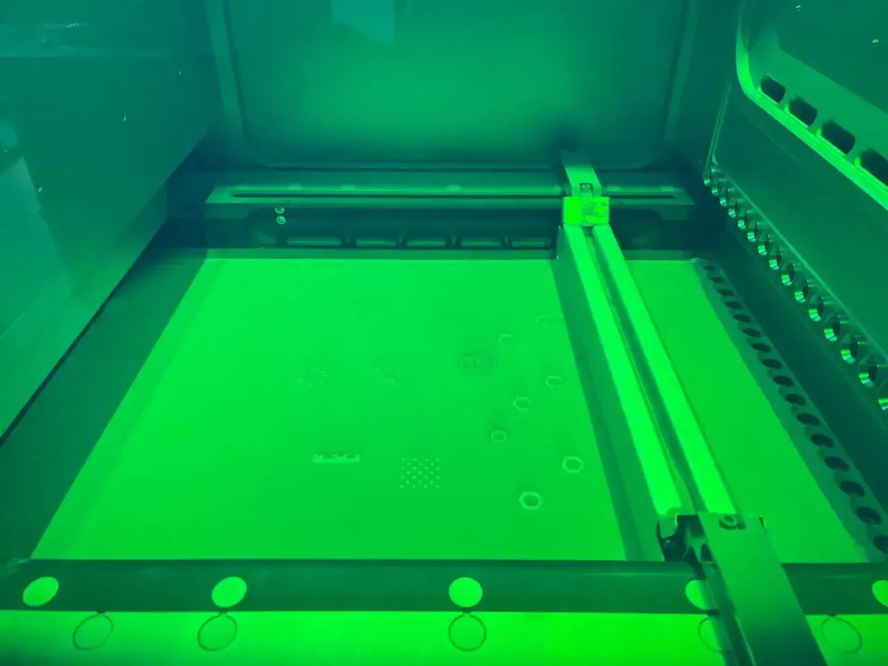Wnętrze drukarki 3D, gdzie proces binder jetting tworzy drobne detale na zielonej powierzchni.