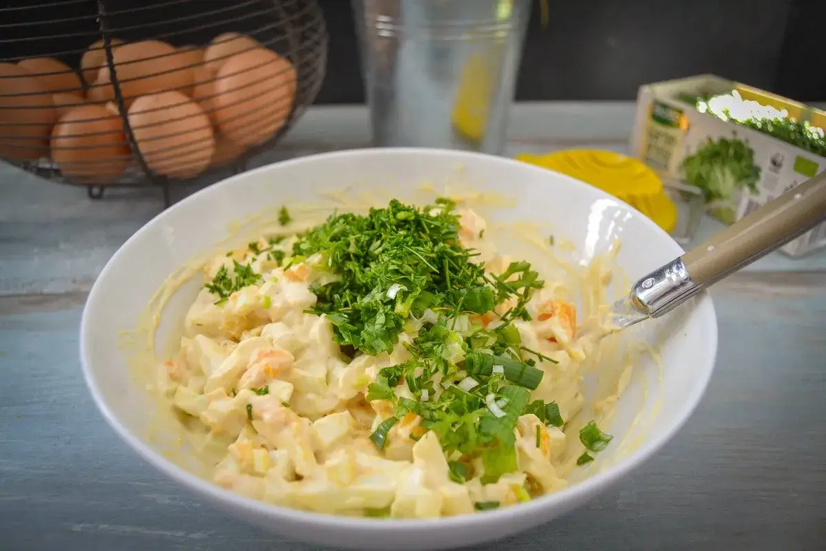 Cremiger eiersalat mit schmand, garniert mit frischen Kräutern und Frühlingszwiebeln. Perfekt für ein leichtes Mittagessen.