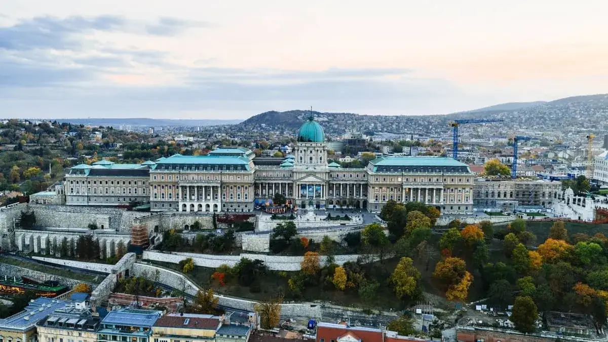 Majestatyczny budapeszt zamek na wzgórzu, otoczony jesiennymi drzewami i miastem.