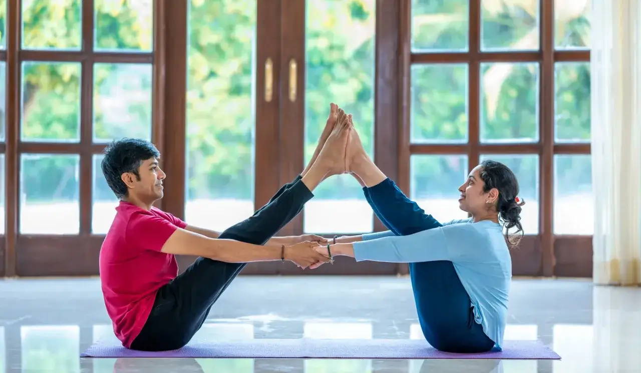 Couple pratiquant le yoga en tandem, une pose qui pourrait vous aider &agrave; d&eacute;cider quel type de yoga choisir.