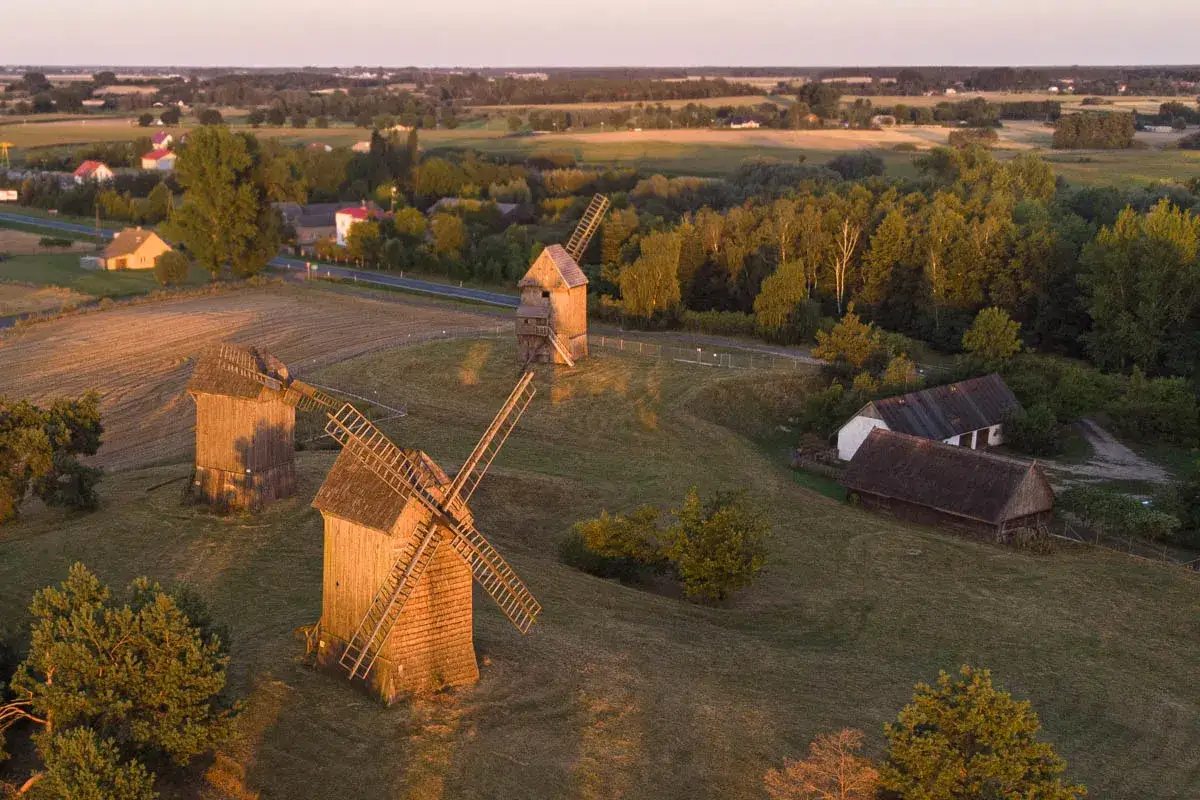 Wielkopolska atrakcje: drewniane wiatraki na tle malowniczego krajobrazu o zachodzie słońca.