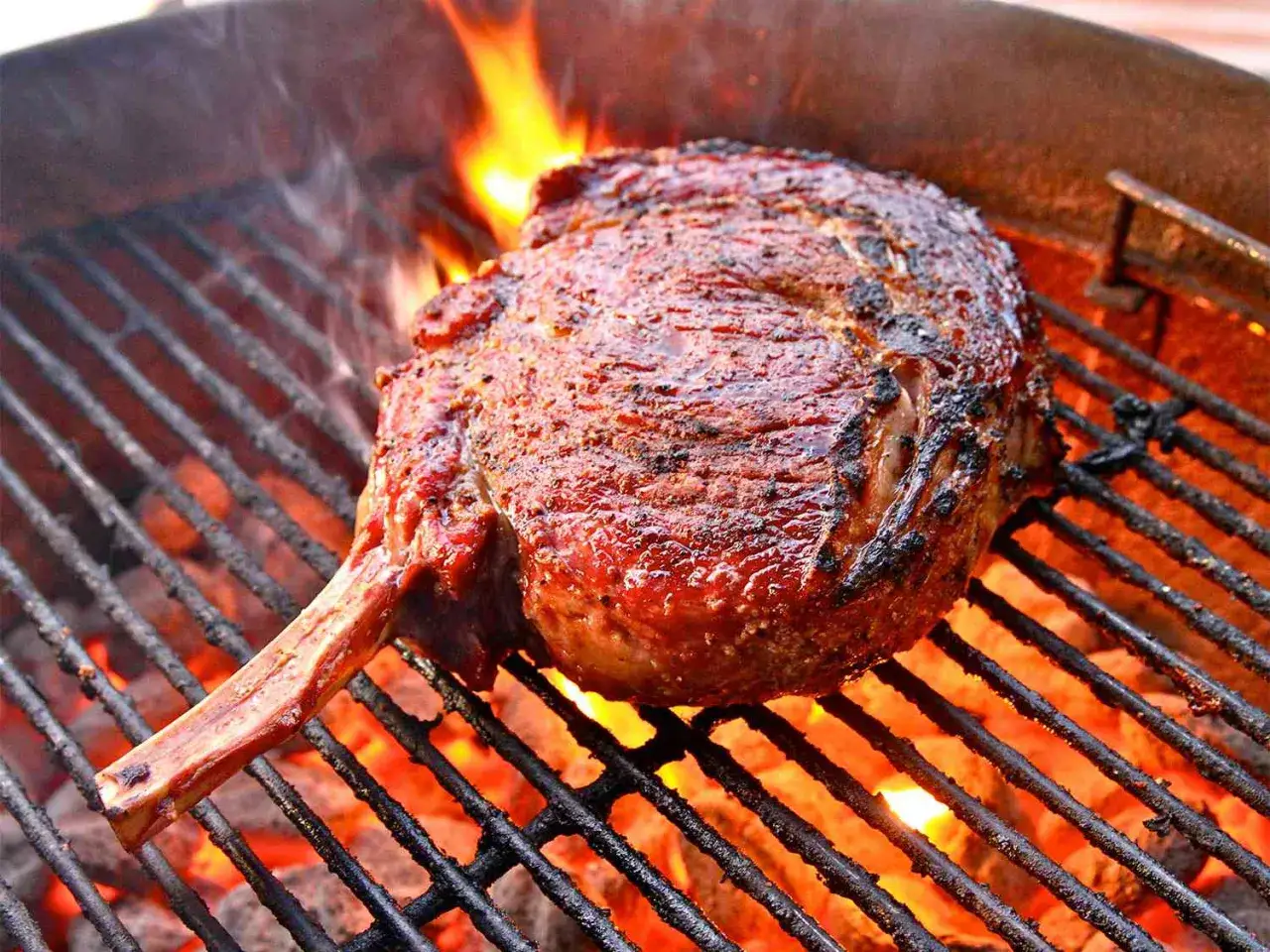Une magnifique côte de bœuf, saisie à la perfection sur un gril incandescent, dégageant une fumée alléchante.