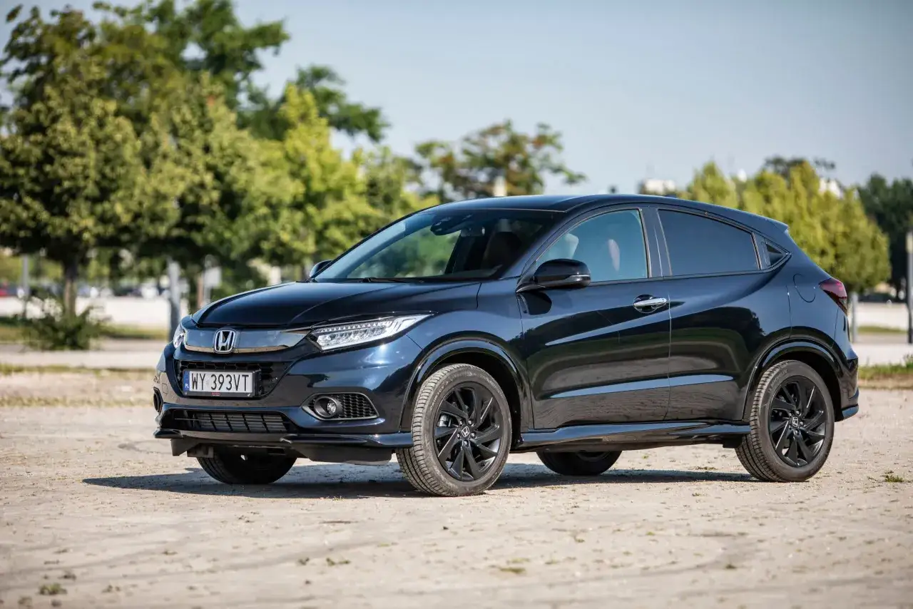 Ciemnogranatowy Honda HR-V na tle drzew. Zbliżenie na przód auta, widoczne światła LED i tablica rejestracyjna. Idealne honda hrv wymiary dla rodziny.