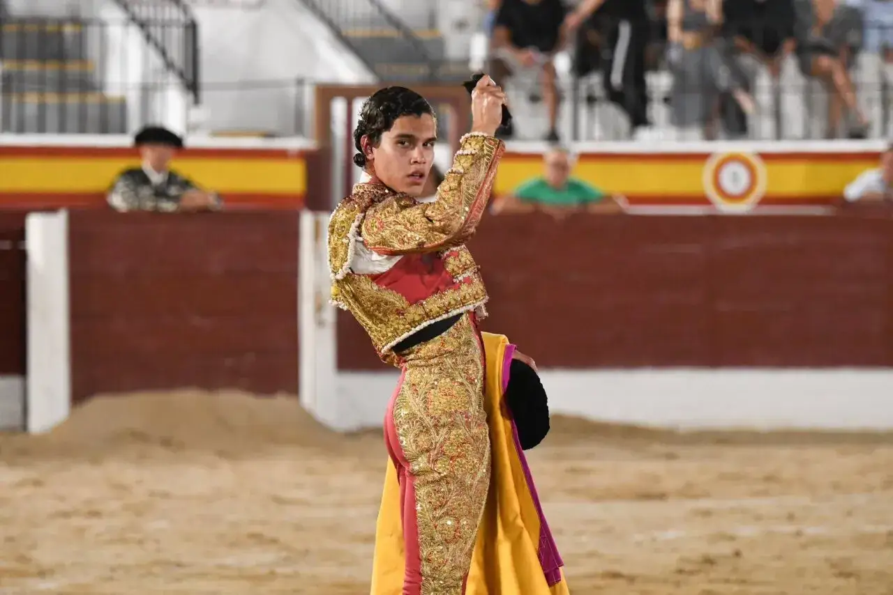 Joao Ferreira, banderillero, con traje de luces dorado y rojo, sostiene un capote en la plaza de toros.