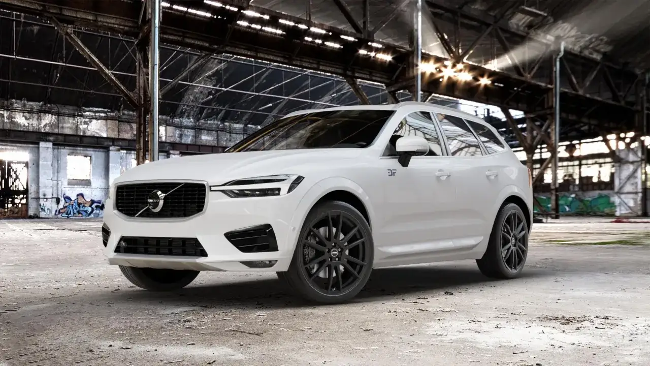 Białe Volvo XC60 z czarnymi felgami i subtelnym tuningiem optycznym, prezentujące się w opuszczonej hali przemysłowej.