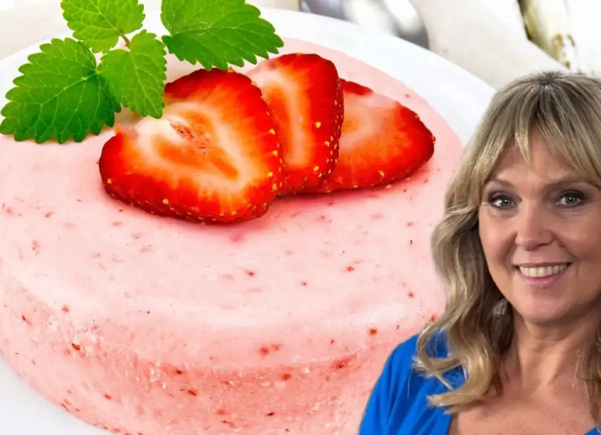 Puszysta pianka truskawkowa z plasterkami owoców i miętą. Uśmiechnięta kobieta w niebieskiej bluzce obok deseru.