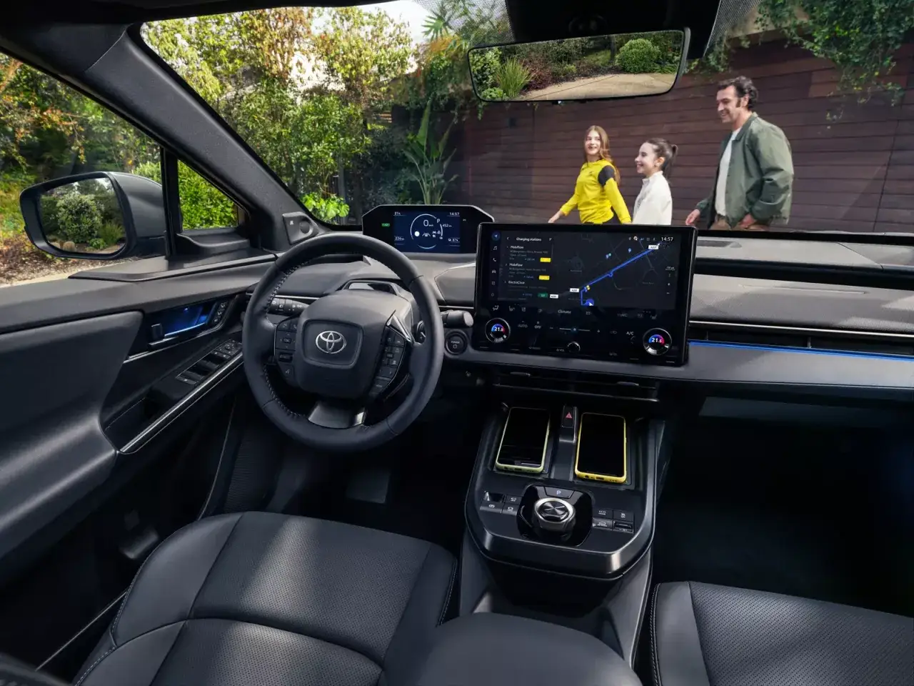 Wnętrze Toyoty bZ4X z ekranem nawigacji. Rodzina idzie obok, zastanawiając się nad ceną tego elektryka.