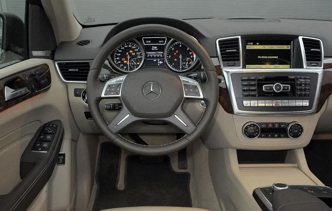 Wnętrze m class mercedes benz: kierownica, deska rozdzielcza z ekranem multimediów i panelem klimatyzacji.